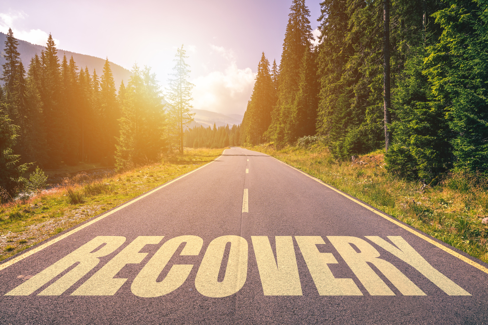 A tree-lined road with the word "recovery" in the center