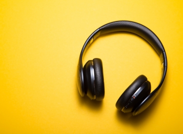 Black headphones on a yellow background. Photo by Malte Wingen on Unsplash