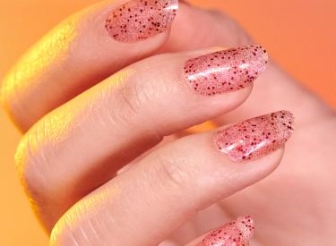 A close up of a pink sparkly manicure