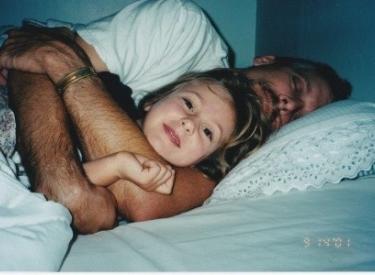 An old family photo of a young Emilia and her dad cuddling happily