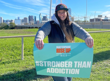 Ashley Riley holding up a sign that says Stronger Than Addiction