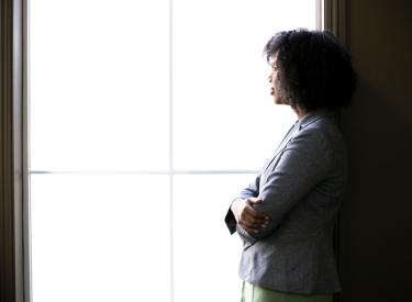 Woman staring out a bright window and looking pensive 