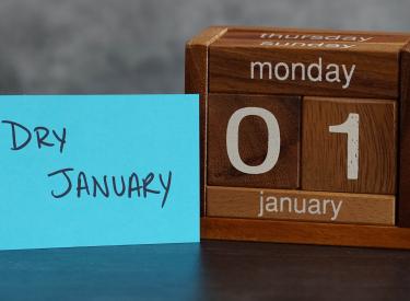 A postcard saying "Dry January" propped up next to a wooden calendar