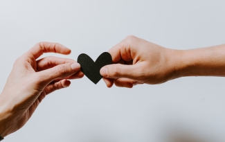 Two hands holding a cut-out of a heart. Image by Kelly Sikkema via Unsplash.